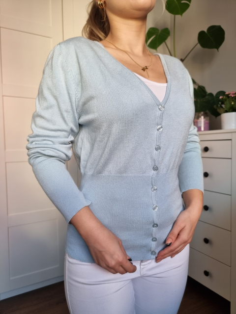 Jasnoniebieski swetrek na guziki podkreślający figurę Jasnoniebieski swetrek na guziki podkreślający figurę